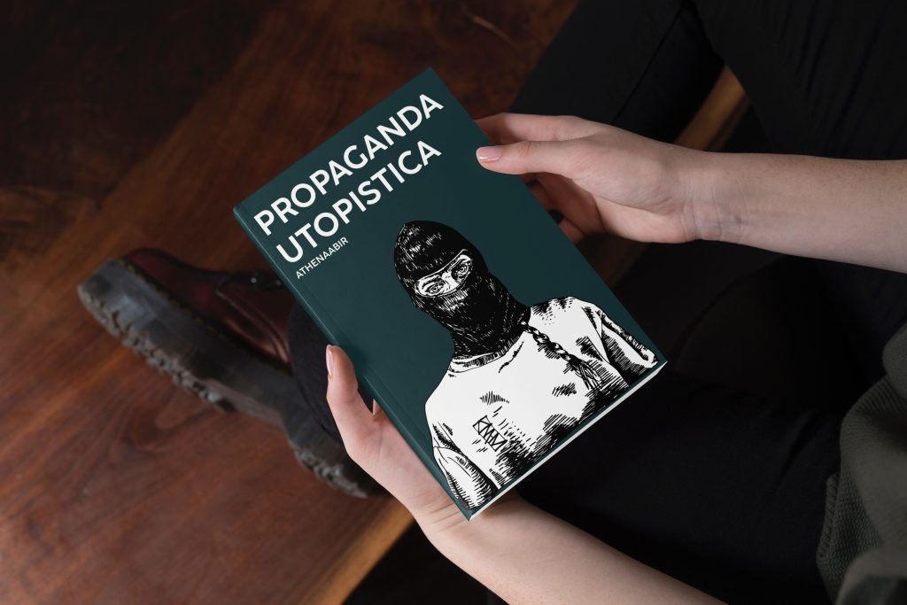 Mani che tengono un libro intitolato “Propaganda Utopistica” con copertina verde scuro e illustrazione in bianco e nero di una persona con passamontagna
